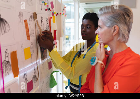 Female fashion designers discussing over sketch design Stock Photo