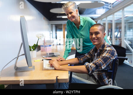 Male and female executives working together on computer at desk in office Stock Photo