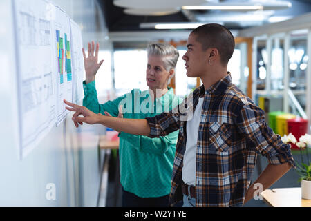 Male and female architects discussing over an architectural plan in office Stock Photo