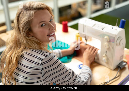 Female fashion designer using sewing machine on a table in design studio Stock Photo