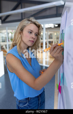 Female architect working over blueprint on whiteboard in a modern office Stock Photo