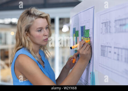 Female architect working over blueprint on whiteboard in a modern office Stock Photo