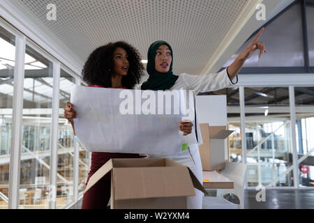 Female executives discussing over blueprint in office Stock Photo