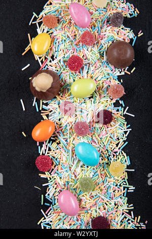 variety of candies on a wooden background with space for text. Colorful sugar sprinkles. Easter Stock Photo
