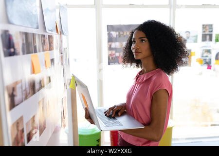 Female graphic designer using laptop in office Stock Photo
