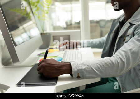 Male graphic designer using graphic tablet at desk Stock Photo