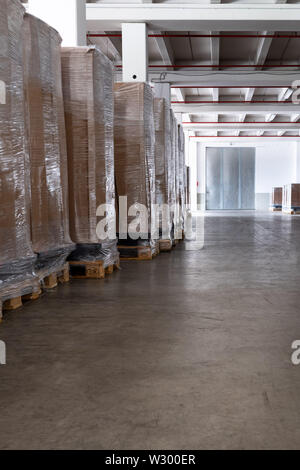 Pallets with cartons and packaging foil are stored in a clean storage room. Stock Photo