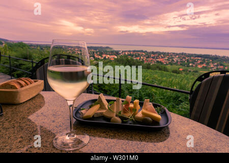 Wine, cheese table over the Lake Balaton on the hill Dinner, lunch, romantic date, picnic, eating on nature. Csopak wine restaurant at sunset Hungary Stock Photo