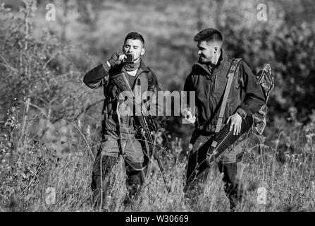 Man hunters with rifle gun. Boot camp. Hunting skills and weapon equipment. How turn hunting into hobby. Military uniform fashion. Friendship of men hunters. Hunter aiming rifle in forest. Stock Photo