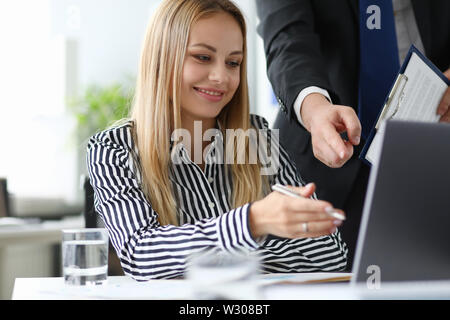 Portrait of smiling business lady discussing with partner conditions of contract. Cheerful businesswoman reading and correcting important documents. B Stock Photo