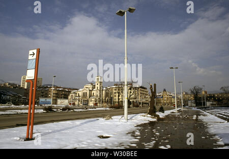 2nd April 1993 During the Siege of Sarajevo: the view east along 'Sniper Alley' (Zmaja od Bosne) towards the city centre, from the front of the Assembly Building. In the centre is Saint Joseph’s Church (Roman Catholic); on the right, the burnt-out shell of the old tobacco factory. Behind the signpost on the left is the Dr Abdulah Nakas General Hospital, known locally as the 'City' or 'French' Hospital during the war. Stock Photo