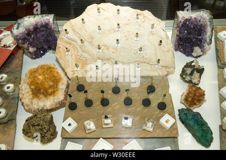 A shop display case of earrings, necklaces and rings with various local cut precious gems and sapphires in a Gem shop in  Sapphire, a small town in th Stock Photo