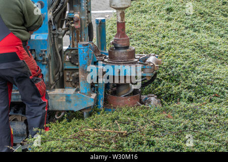 Hollow borehole auger of a dry drilling rig drills a hole in the sandy soil and produces sand on the sides, work Stock Photo