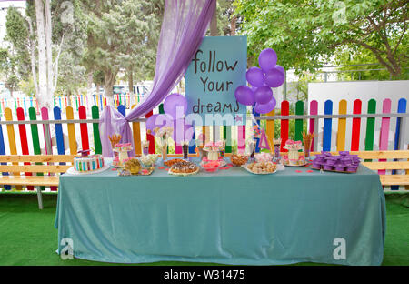 Candy bar with cupcakes, marshmallows, cakes, meringues.Candy bar for children's birthday.Beautiful birthday cake with pink decor for the birthday of Stock Photo