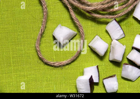Pieces of coconut and jute rope on a green background Stock Photo