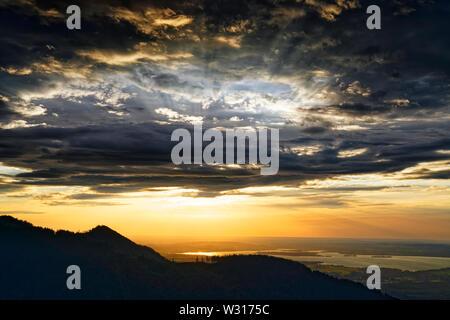 Beautiful sunset over lake Chiemsee with cloudy sky on Hochfelln mountain Stock Photo