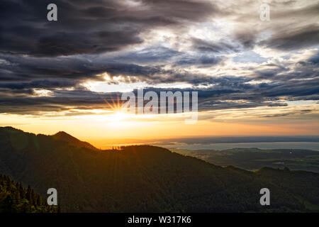 Beautiful sunset over lake Chiemsee with cloudy sky on Hochfelln mountain Stock Photo