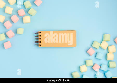 Marshmallow and blank notepad on blue background. Place for your text. Cozy sweet background Stock Photo