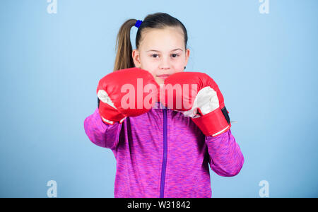 With great power comes great responsibility. Contrary to stereotype. Boxer child in boxing gloves. Female boxer. Sport upbringing. Boxing provide strict discipline. Girl cute boxer on blue background. Stock Photo