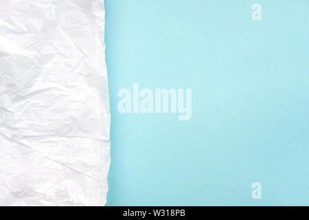 Crumpled white parchment paper on bright blue, turquoise background top view. Rough, wrinkled, damaged paper texture. Abstract design, creased, aged s Stock Photo