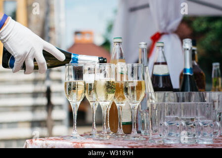Bartender pours champagne. A lot of wine glasses with cool delicious champagne or white wine. Party and holiday celebration concept Stock Photo
