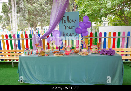 Candy bar with cupcakes, marshmallows, cakes, meringues.Candy bar for children's birthday.Beautiful birthday cake with pink decor for the birthday of Stock Photo