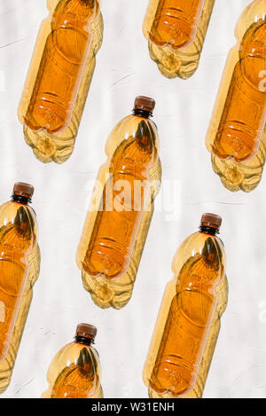 Bottles of brown color lie on a white background in a row. The bright sun shines on colored plastic, creating a shadow from the bottle. Production of Stock Photo