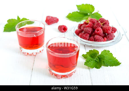 Raspberry liqueur in glass and fresh berries on a white background. Alcoholic flavored drink. Stock Photo