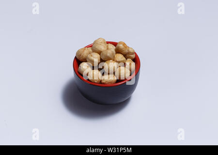 Front view of hazelnuts inside a red bowl isolated on white background. Stock Photo