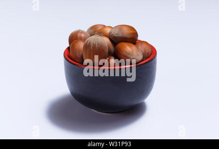 Front view of hazelnuts inside a red bowl isolated on white background. Stock Photo