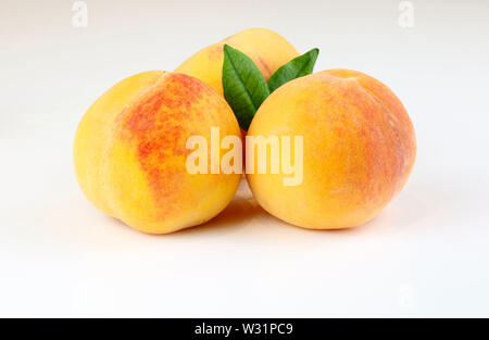Fresh peaches with green leaves isolated on white background Stock Photo