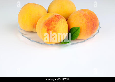 Fresh peaches with green leaves isolated on white background Stock Photo