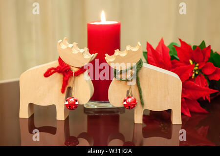 Christmas decor in modern interior. Scandinavian style, hygge. Christmas toys moose deer with red and green ropes tied around neck and bells with lit Stock Photo