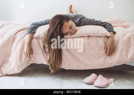 Sad or upset girl lying in bed. She is ill, lonely or in a bad mood or other problems. Stock Photo