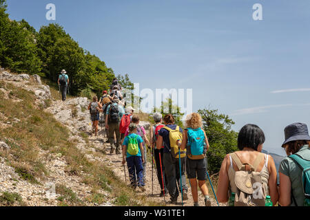 Subiaco RM, Italy - 07 July 2019: Group of hikers on the mountain path, go up the slope of Mount Autore. Stock Photo