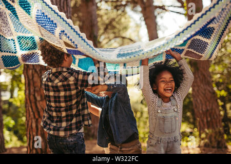 Four kids in park with picnic blanket. Group of children enjoying together in park. Stock Photo