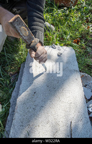 Top view of an artist carving in stone using mallet and a chisel. Stock Photo