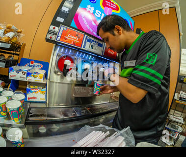A worker fills a Slurpee in a 7-Eleven store in New York on Thursday, July 11, 2019 (7-11, get it?),the self-proclaimed holiday Free Slurpee Day! The popular icy, slushy, syrupy drinks are available in regular and diet flavors, in combinations, and the stores have stocked up with extra barrels of syrup to meet the expected demand. According to the meticulous figures kept by 7-Eleven they sell an average of 14 million Slurpees a month and over 150 million Slurpees a year.  (© Richard B. Levine) Stock Photo