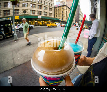 A slurpee lover displays her free Slurpees outside a 7-Eleven store in New York on Thursday, July 11, 2019 (7-11, get it?),the self-proclaimed holiday Free Slurpee Day! The popular icy, slushy, syrupy drinks are available in regular and diet flavors, in combinations, and the stores have stocked up with extra barrels of syrup to meet the expected demand. According to the meticulous figures kept by 7-Eleven they sell an average of 14 million Slurpees a month and over 150 million Slurpees a year.  (© Richard B. Levine) Stock Photo