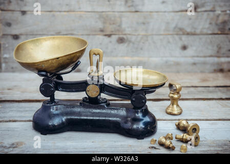 Antique vintage measuring scale weights with brass trays on the wooden rustic background. Selective focus, copy space Stock Photo