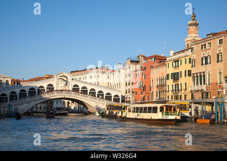 Rialto Bridge and Grand Canal at sunset with tourists lining the bridge and a vaporetto water bus at the Rialto station, Venice, Veneto, italy Stock Photo