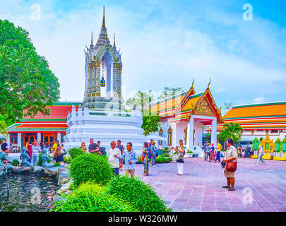 BANGKOK, THAILAND - APRIL 22, 2019: The small carved belfry with tiled decorations is topped on the stone foundation in the middle of the courtyard of