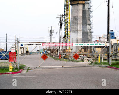 Closed chain link gate with signs designating a secure area at the Port of Corpus Christi, Texas USA. Harbor Bridge column construction in frame. Stock Photo