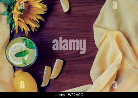 Mint lemonade with lemon slices on a wooden background with a beautiful sunflower, still life photography, above vantage point photography Stock Photo