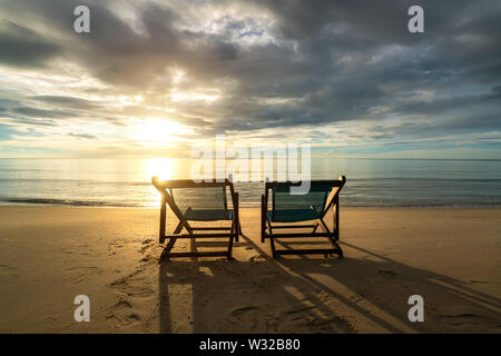 Two deckchairs on the beach at sunset with a tropical sea background. Travel and Vacation in Summer at sea. Stock Photo