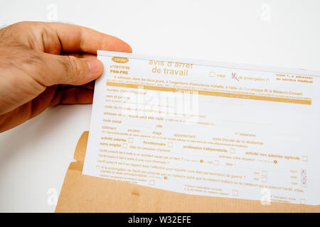 Paris, France - Jun 19, 2019: Patient male man holding above white executive table the Avis d'arret de travail Sick leave issued by treating doctor medical justification Stock Photo