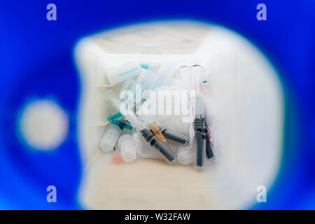 Macro view inside container cleared sharps disposal container with multiple used needles and other sharps medical objects inside Stock Photo