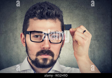 Young man holding a processor memory card by his head. Stock Photo