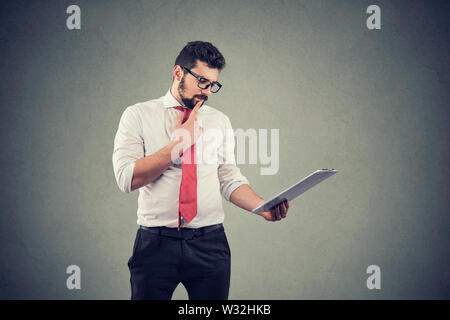 Thoughtful business man touching chin and using tablet computer Stock Photo