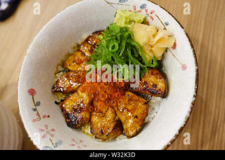 Grilled foie gras garnished with salmon roe, pickled ginger and spring onions on top of steamed hot rice is one of the dishes in Gojuu Sushi. Stock Photo